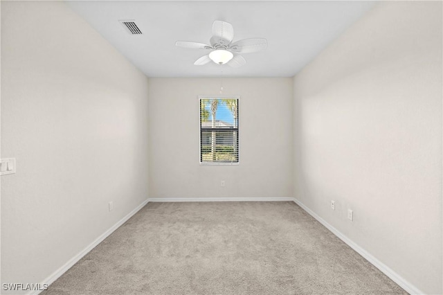 carpeted spare room with a ceiling fan, visible vents, and baseboards