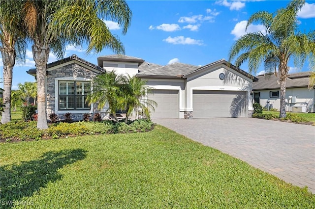 ranch-style house featuring decorative driveway, stucco siding, an attached garage, stone siding, and a front lawn