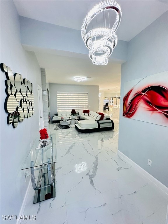 interior space featuring marble finish floor, a notable chandelier, and baseboards