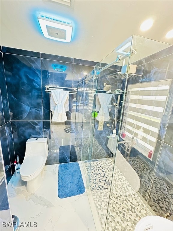 bathroom featuring a stall shower, marble finish floor, tile walls, and toilet