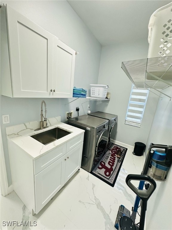 laundry room featuring marble finish floor, washing machine and clothes dryer, a sink, and cabinet space