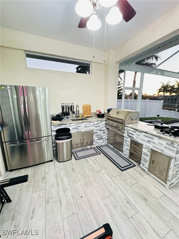 kitchen with ceiling fan, a sink, light countertops, light wood-type flooring, and freestanding refrigerator