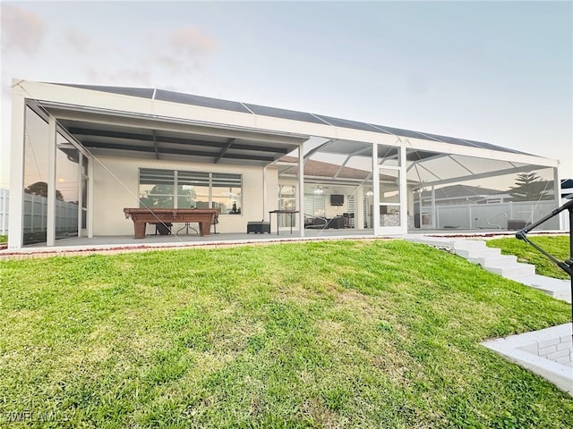 rear view of property featuring a lanai, stucco siding, a lawn, and a patio