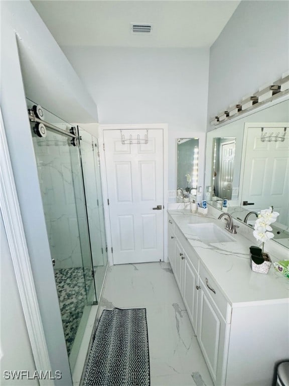 full bath with double vanity, a marble finish shower, visible vents, marble finish floor, and a sink