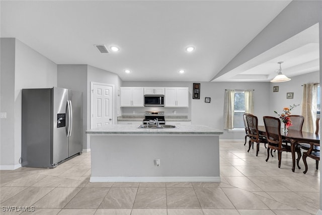 kitchen with a kitchen island with sink, a sink, white cabinetry, appliances with stainless steel finishes, and light stone countertops