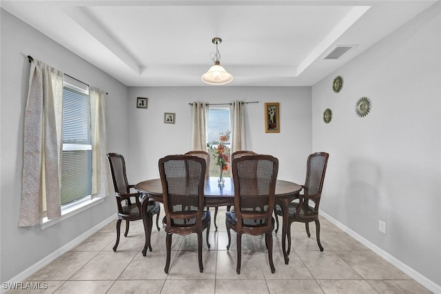 dining room featuring a raised ceiling, visible vents, and baseboards