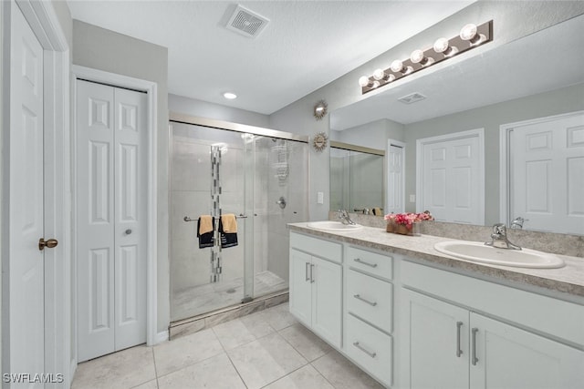 bathroom with a closet, visible vents, a sink, and a shower stall