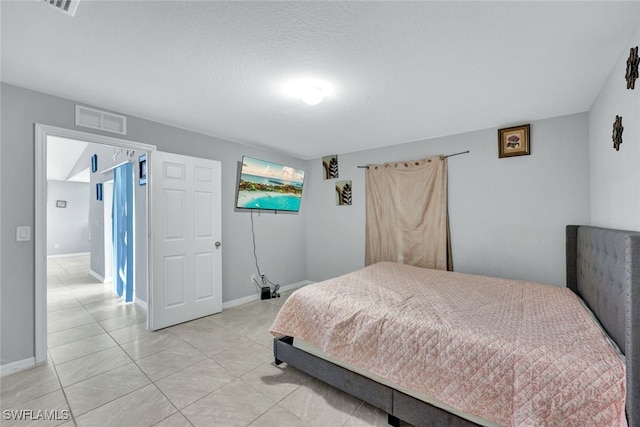 bedroom with baseboards, visible vents, a textured ceiling, and light tile patterned flooring