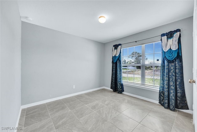 unfurnished room with light tile patterned flooring and baseboards