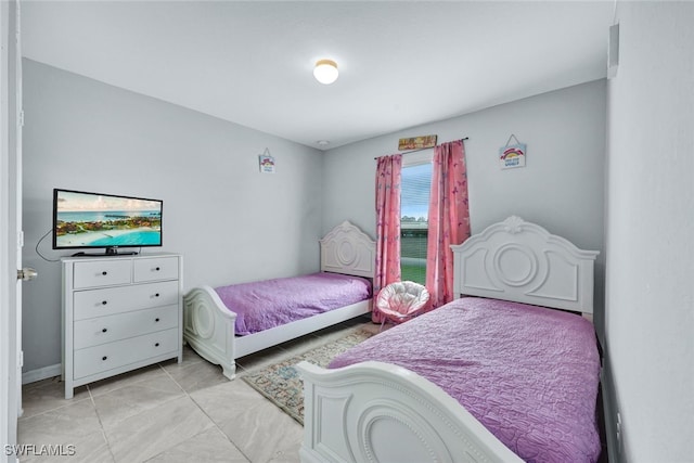 bedroom with light tile patterned floors and baseboards