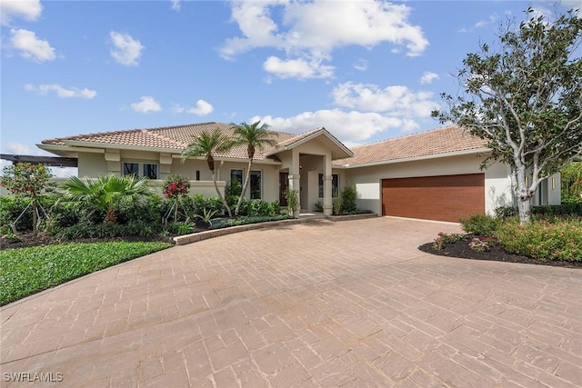 view of front of house featuring a garage, decorative driveway, a tile roof, and stucco siding