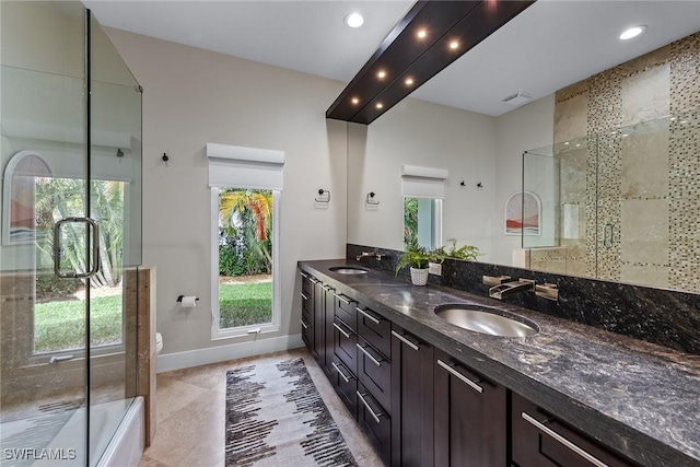 bathroom with double vanity, toilet, a sink, and a shower with shower door