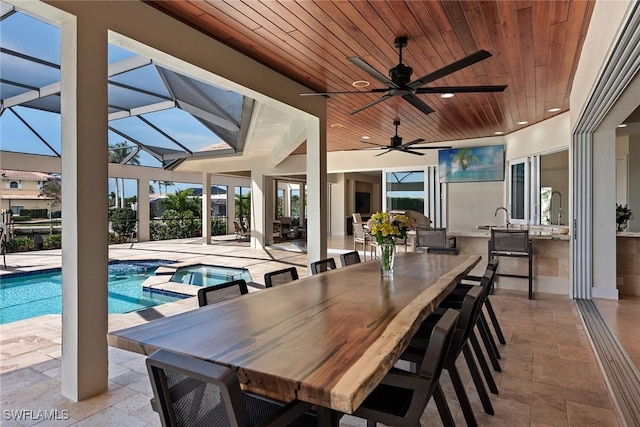 exterior space featuring outdoor dining area, a pool with connected hot tub, a ceiling fan, a patio area, and a lanai