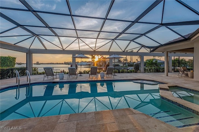 pool at dusk featuring a patio area, a pool with connected hot tub, and glass enclosure