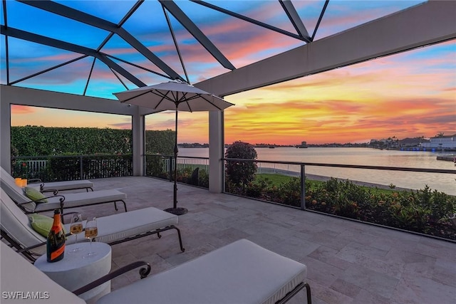 view of patio featuring a lanai and a water view