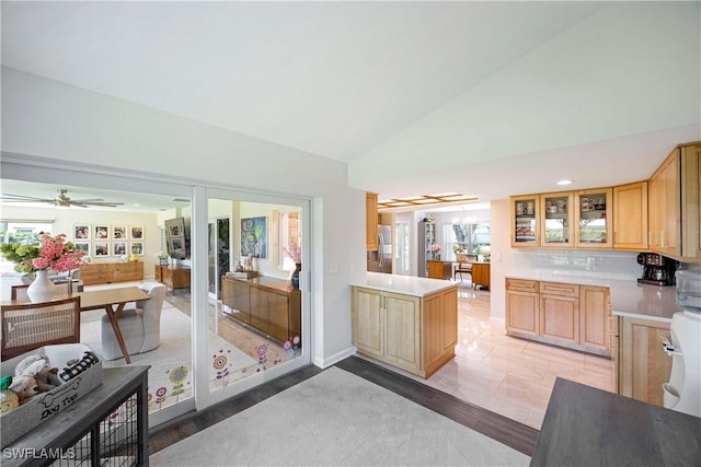 kitchen featuring a peninsula, glass insert cabinets, light countertops, and light brown cabinetry