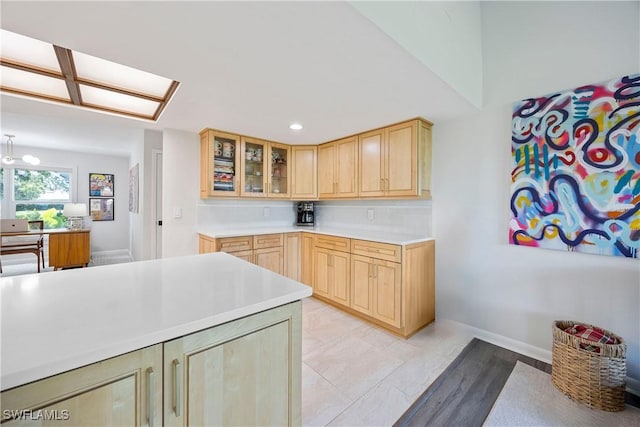 kitchen featuring recessed lighting, glass insert cabinets, light countertops, and light brown cabinetry