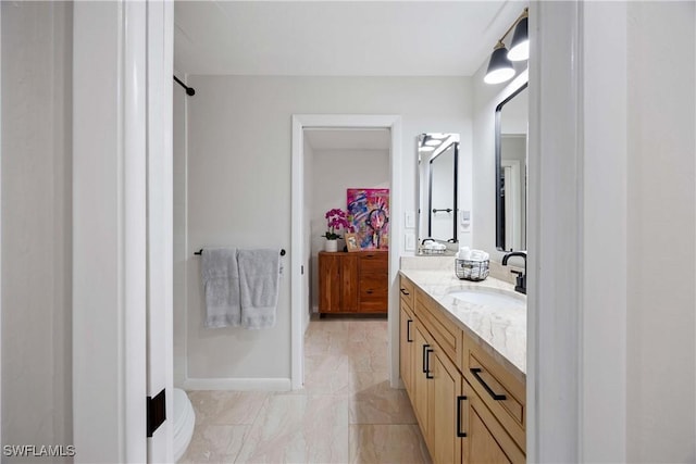 bathroom with marble finish floor, baseboards, and vanity