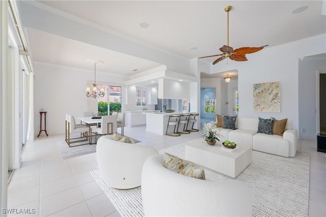 living area with ornamental molding, light tile patterned flooring, and ceiling fan with notable chandelier