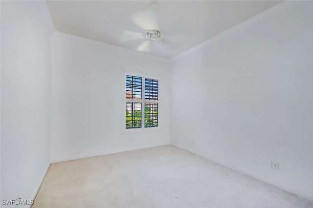 carpeted spare room featuring a ceiling fan and crown molding