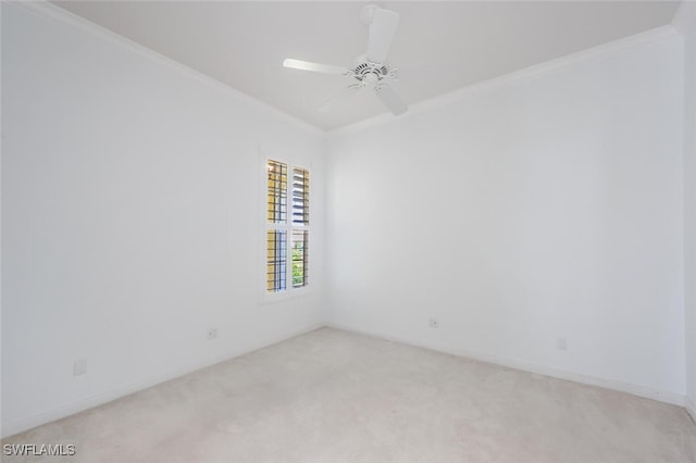 empty room with a ceiling fan, light colored carpet, and crown molding