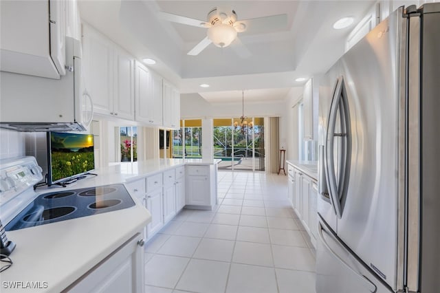 kitchen featuring a tray ceiling, range with electric stovetop, light countertops, freestanding refrigerator, and white cabinets