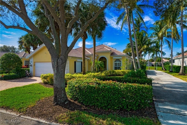 mediterranean / spanish house featuring a tiled roof, decorative driveway, an attached garage, and stucco siding