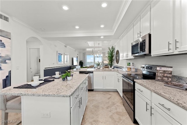 kitchen featuring a peninsula, appliances with stainless steel finishes, white cabinetry, and crown molding