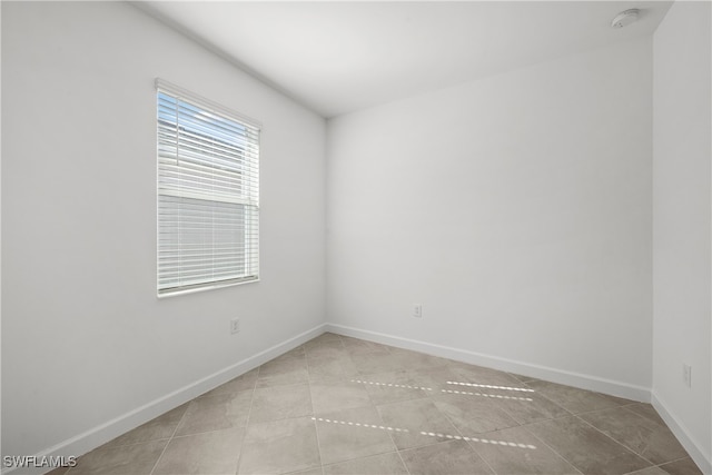 spare room featuring light tile patterned flooring and baseboards