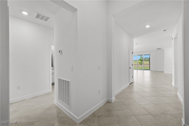 hall with visible vents, baseboards, and light tile patterned floors