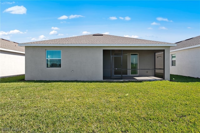 rear view of property with a sunroom, roof with shingles, a lawn, and stucco siding