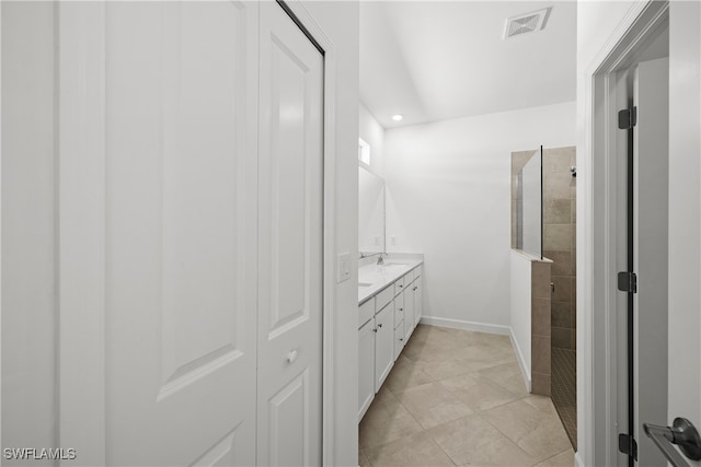 full bathroom with double vanity, a closet, visible vents, a walk in shower, and baseboards