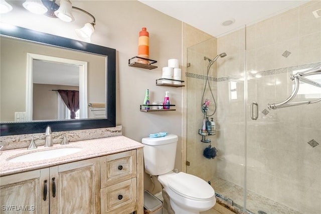 bathroom with toilet, a shower stall, and vanity