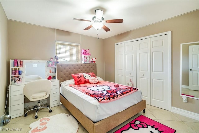 bedroom with a closet, light tile patterned flooring, ceiling fan, and baseboards