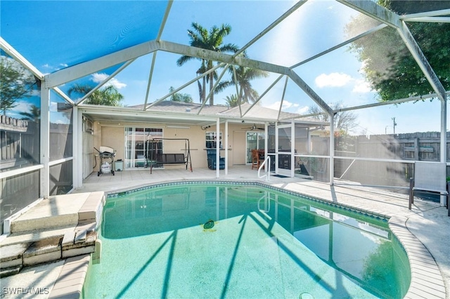 outdoor pool featuring a lanai, a patio area, a grill, and fence