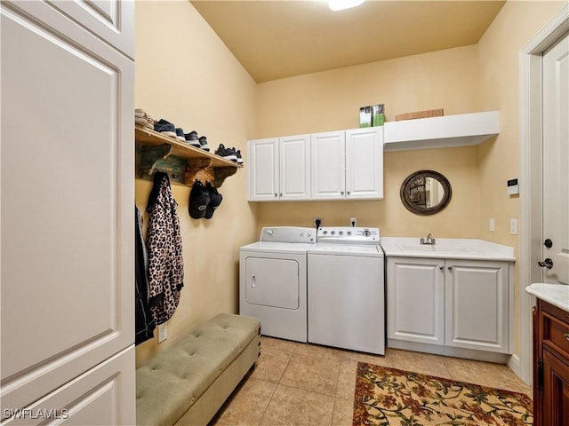 washroom with washing machine and dryer, cabinet space, a sink, and light tile patterned flooring