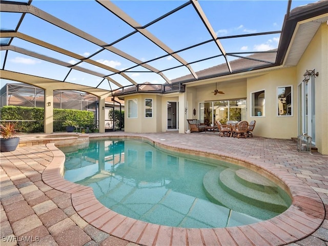 view of swimming pool with a patio area, a pool with connected hot tub, glass enclosure, and ceiling fan