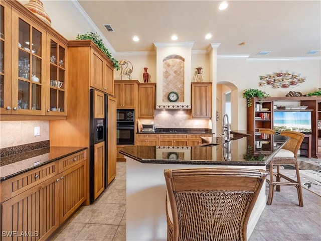 kitchen with arched walkways, a sink, visible vents, decorative backsplash, and black appliances