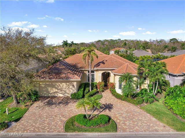 mediterranean / spanish house featuring a garage, decorative driveway, and stucco siding