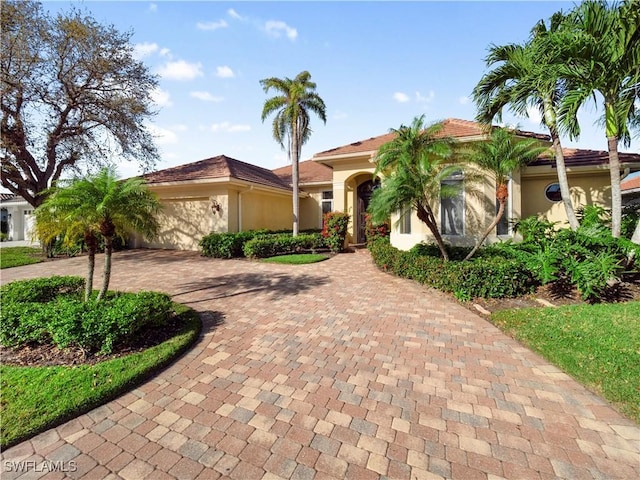 view of front of property featuring decorative driveway, an attached garage, and stucco siding