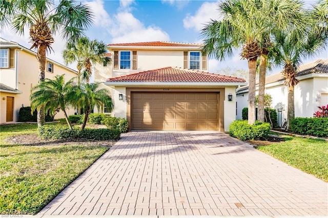 mediterranean / spanish home with an attached garage, a tiled roof, decorative driveway, stucco siding, and a front yard