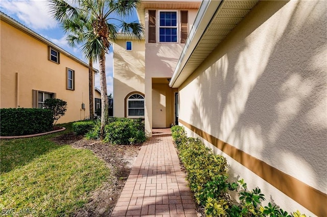 entrance to property with a yard and stucco siding