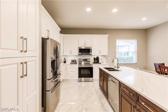 kitchen featuring tasteful backsplash, white cabinets, marble finish floor, stainless steel appliances, and a sink