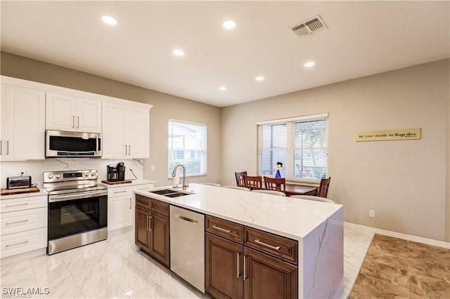 kitchen with visible vents, appliances with stainless steel finishes, a kitchen island with sink, a sink, and plenty of natural light