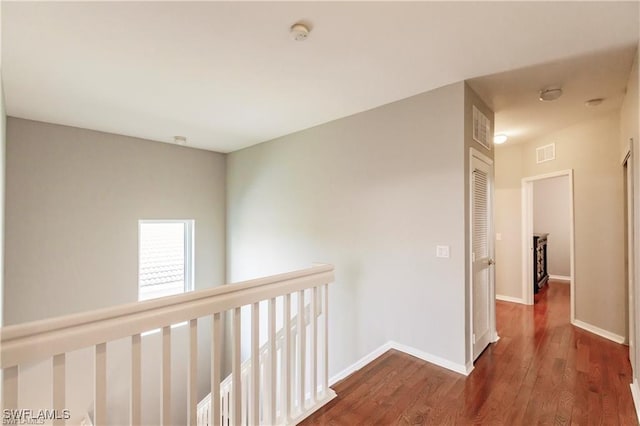 corridor featuring dark wood-style floors, baseboards, and visible vents