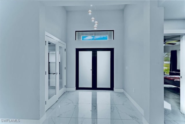 entrance foyer featuring marble finish floor, french doors, and baseboards