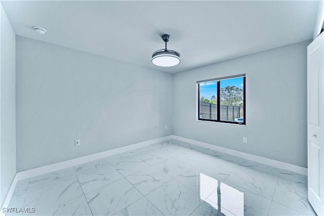 spare room featuring marble finish floor and baseboards