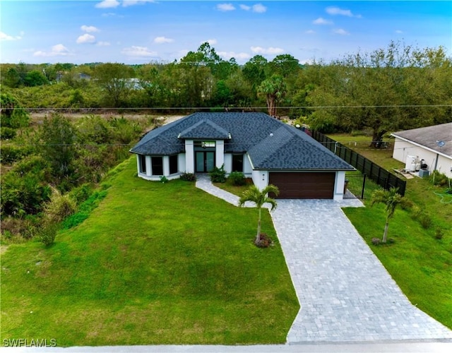 view of front of house with a garage, a front lawn, decorative driveway, and fence