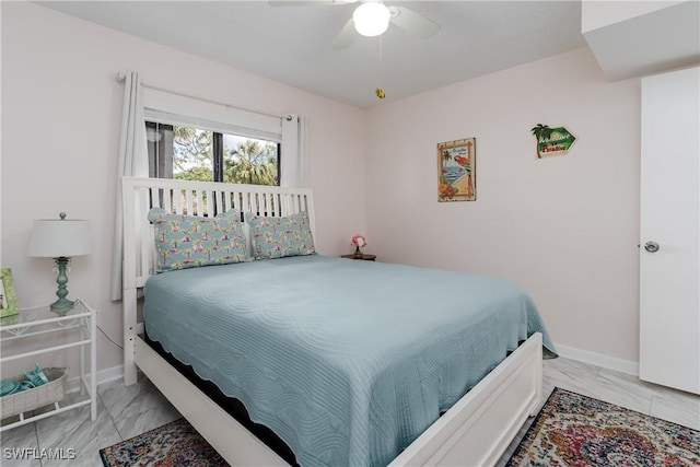 bedroom featuring ceiling fan, marble finish floor, and baseboards