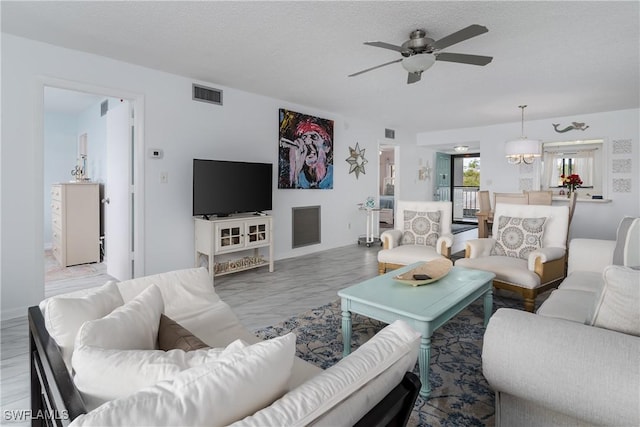 living area featuring a ceiling fan, visible vents, and a textured ceiling